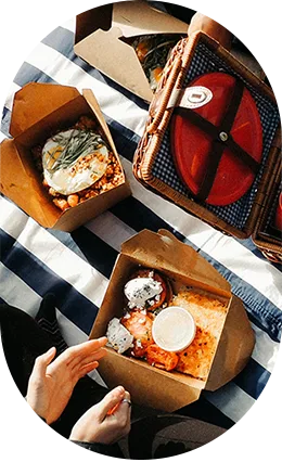 Repas à partager posés sur une nappe rayée, avec un panier de pique-nique