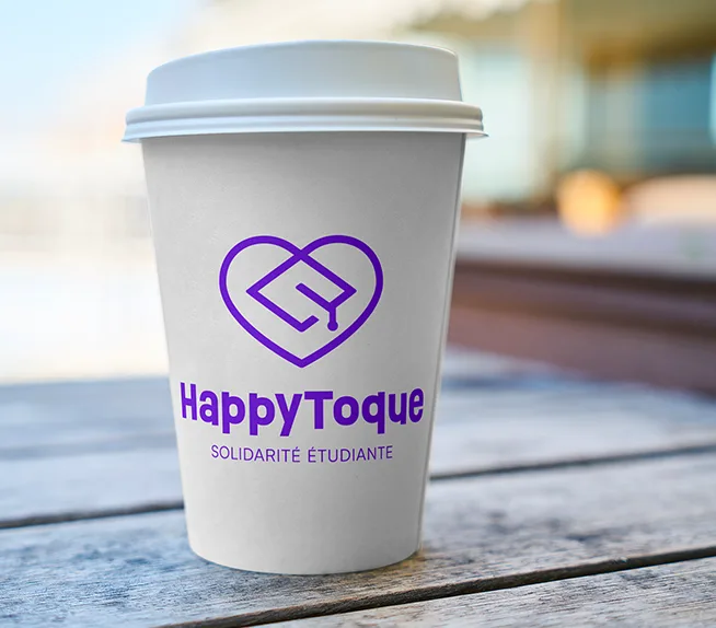 Gobelet de café à emporter portant le logo HappyToque, posé sur une table en bois